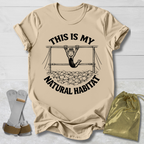 Beige t-shirt with graphic design and text on a light wooden surface.