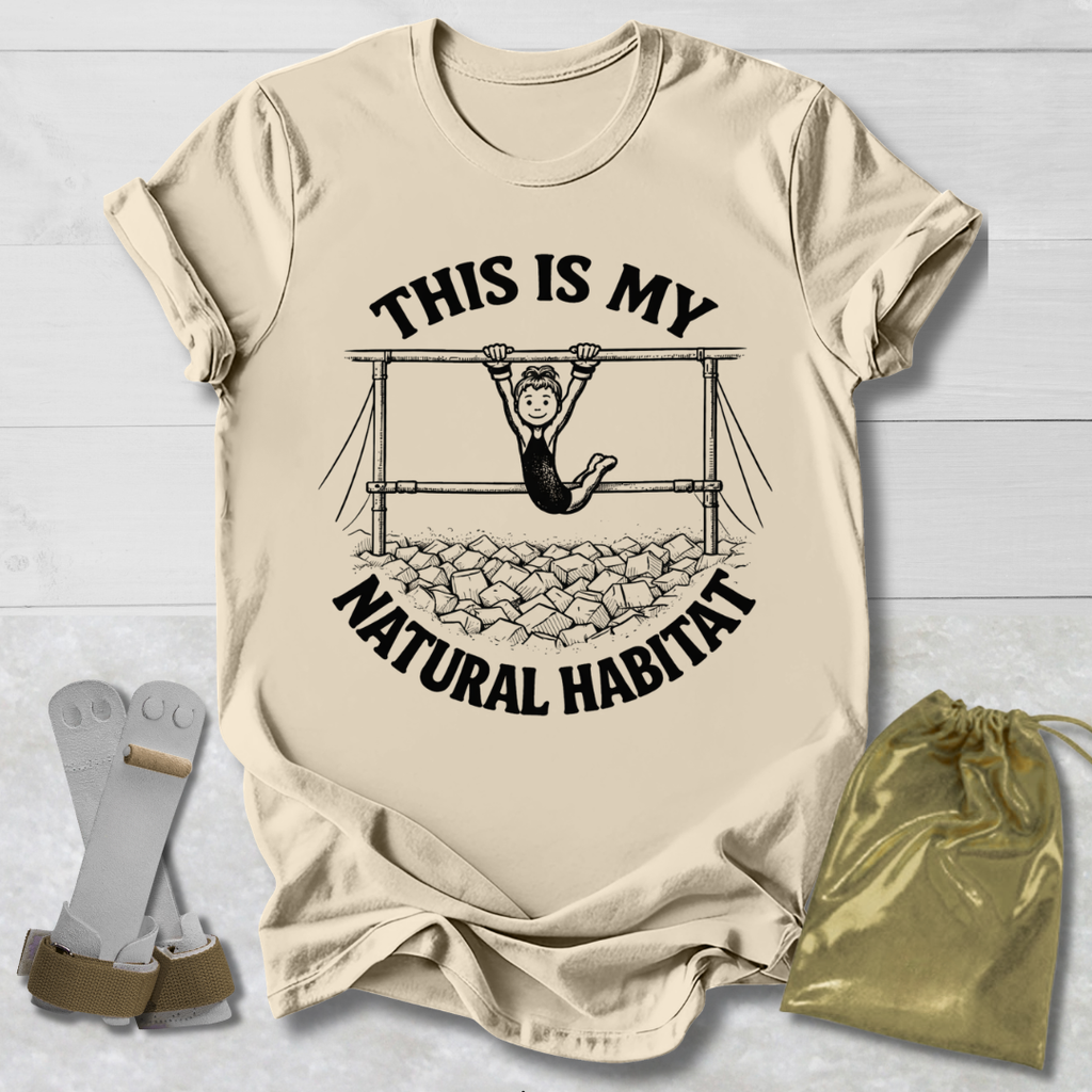 Beige t-shirt with graphic and text 'This is my natural habitat' on a light wooden surface.