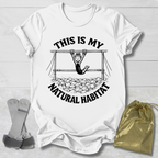 White t-shirt with graphic design and a Gymnast in her natural habitat text on a light wooden surface