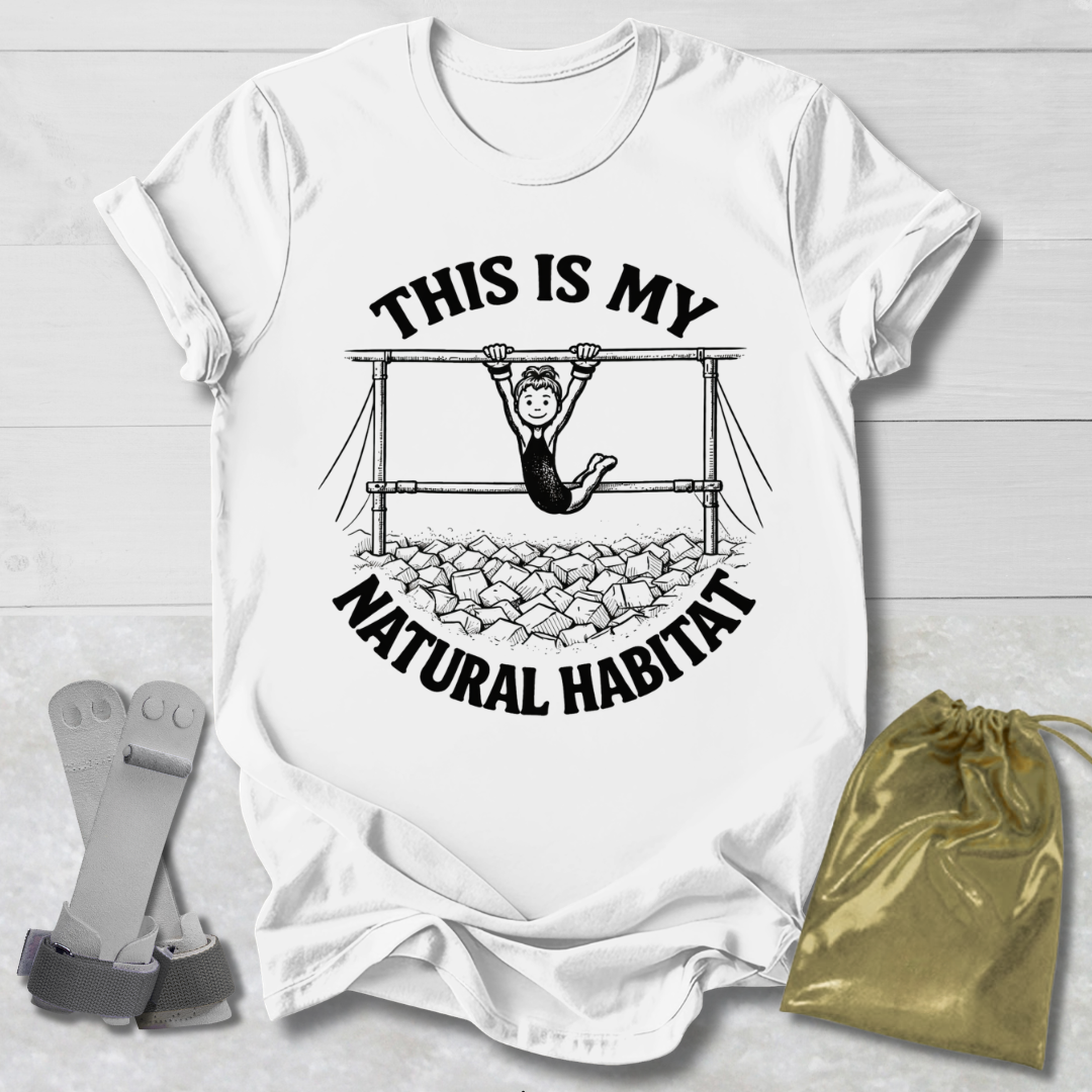 White t-shirt with graphic design and a Gymnast in her natural habitat text on a light wooden surface