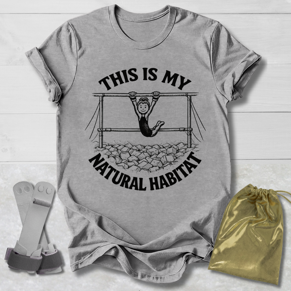 Gray t-shirt with graphic and text 'This is my natural habitat' on a wooden surface with socks and a drawstring bag.