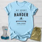 Light blue t-shirt with 'My sport is harder than yours' text, socks, and drawstring bag on a wooden surface.