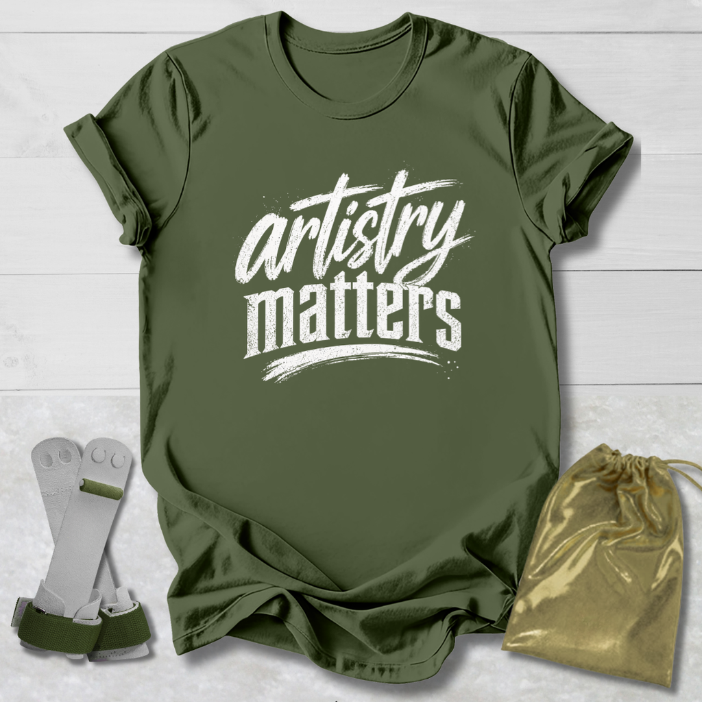 Green t-shirt with 'artistry matters' text, socks, and drawstring bag on a light wooden surface