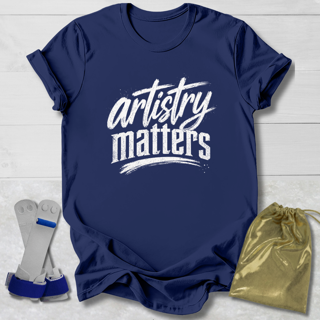 Navy blue t-shirt with 'artistry matters' text, socks, and a drawstring bag on a light wooden surface.