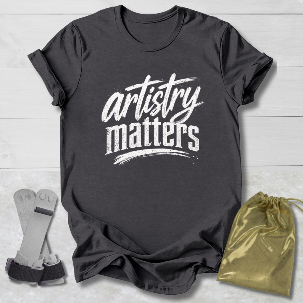 Dark gray t-shirt with 'artistry matters' text, socks, and a drawstring bag on a light wooden surface.
