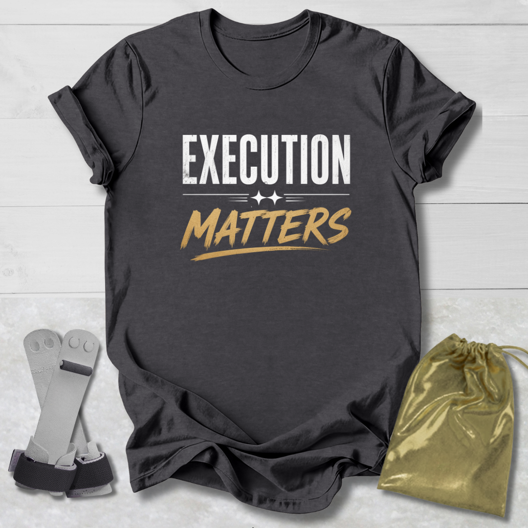 Dark gray t-shirt with 'Execution Matters' text on a light wooden surface with socks and a drawstring bag.