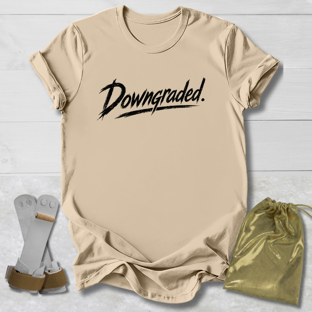 Beige t-shirt with 'Downgraded' text, socks, and drawstring bag on a light wooden surface