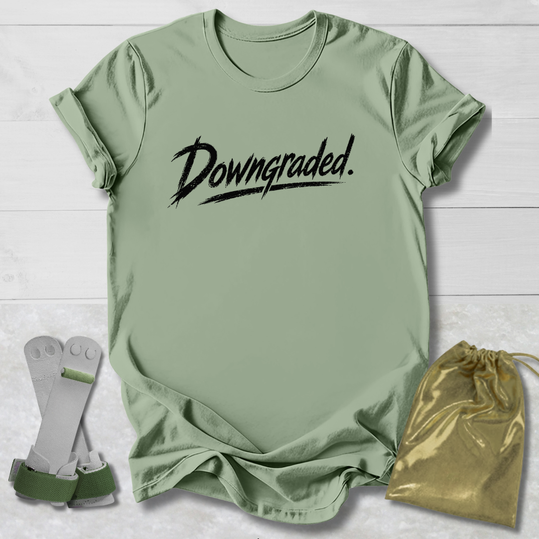 Green t-shirt with 'Downgraded' text, socks, and drawstring bag on a light wooden surface