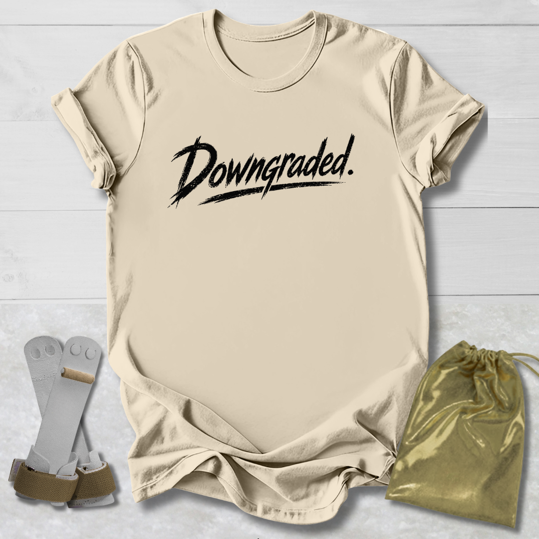 Beige t-shirt with 'Downgraded' text, socks, and drawstring bag on a light wooden surface