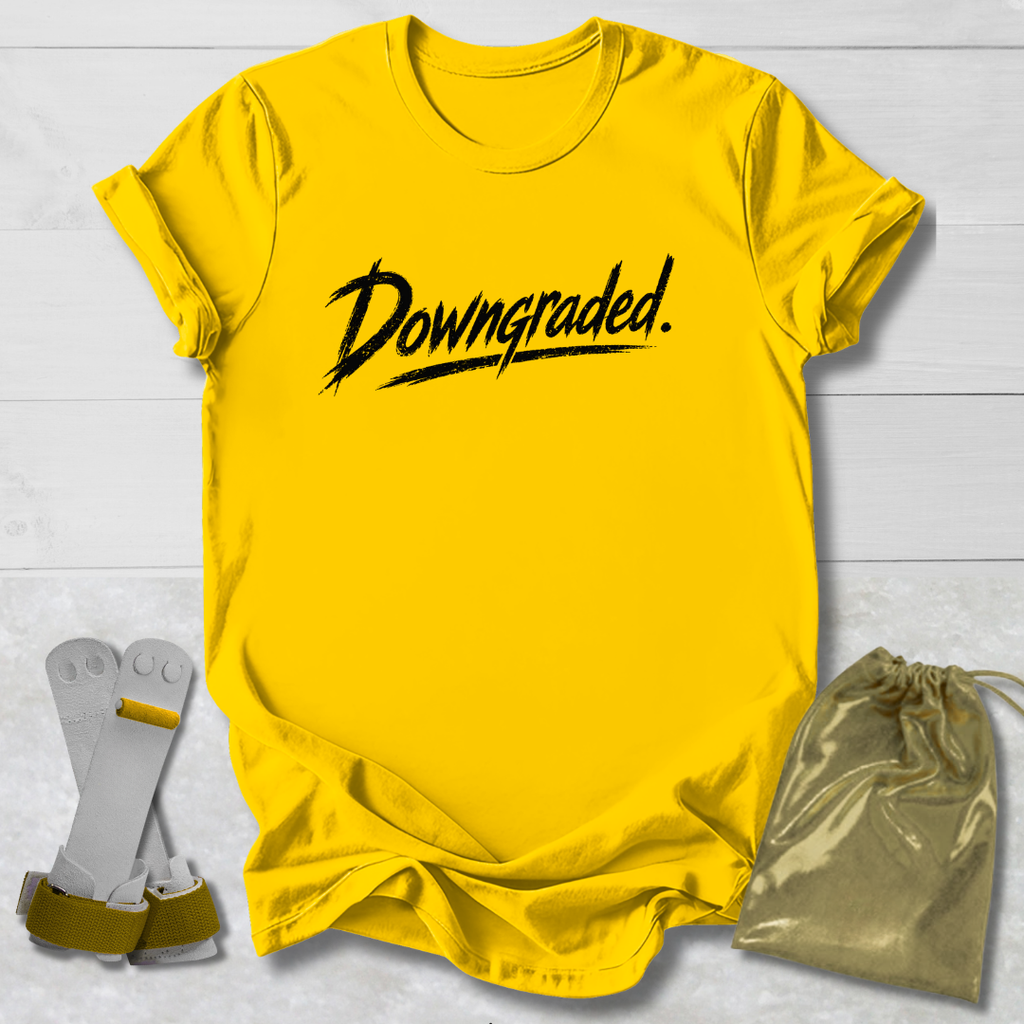 Yellow t-shirt with 'Downgraded' text, socks, and drawstring bag on a light wooden surface