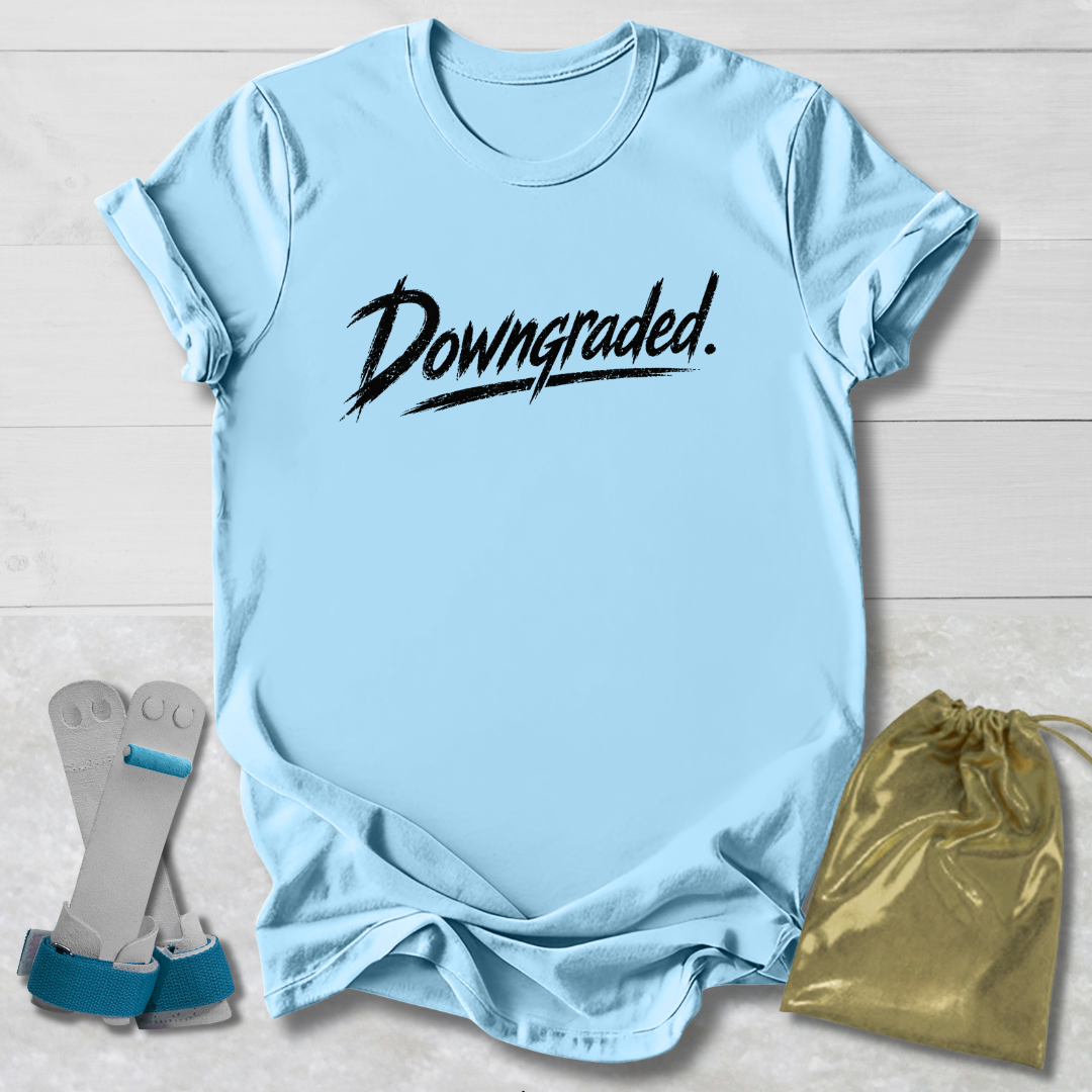 Light blue t-shirt with 'Downgraded' text, socks, and drawstring bag on a light wooden surface