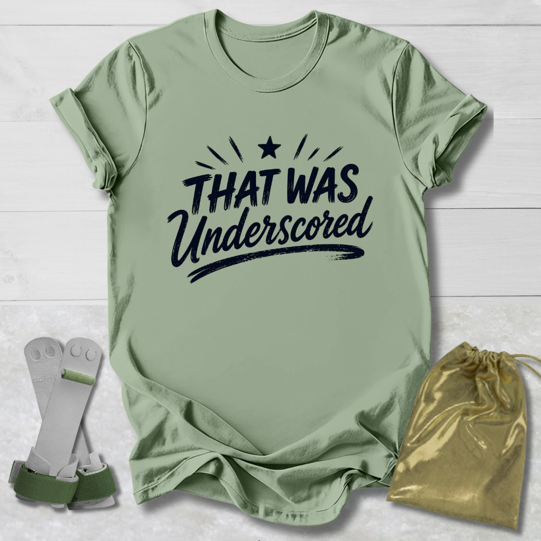 Gray t-shirt with 'THAT WAS Underscored' text, socks, and drawstring bag on a light wooden surface