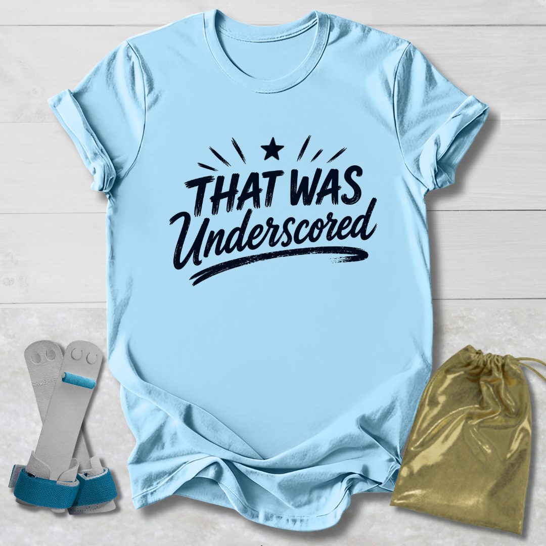 Light blue t-shirt with 'THAT WAS Underscored' text, socks, and drawstring bag on a light wooden surface.