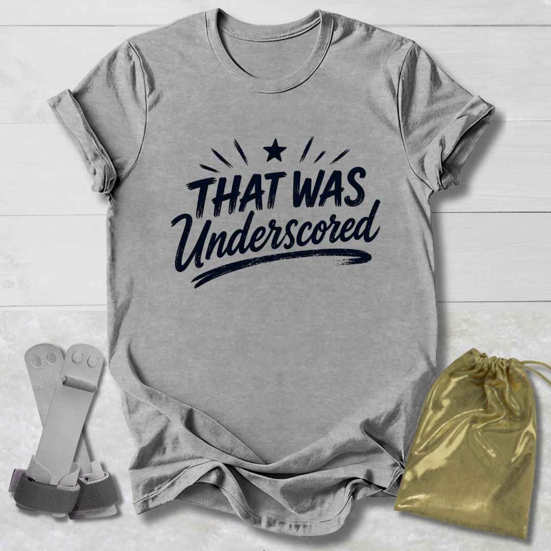 Gray t-shirt with 'THAT WAS Underscored' text, socks, and drawstring bag on a light wooden surface