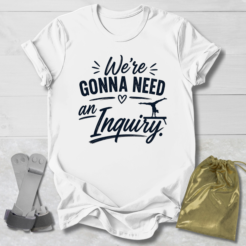 White t-shirt with black text 'We're Gonna Need an Inquiry' on a light wooden surface with socks and a drawstring bag.