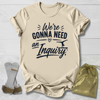 Beige t-shirt with humorous text design on a light wooden surface, accompanied by socks and a drawstring bag.