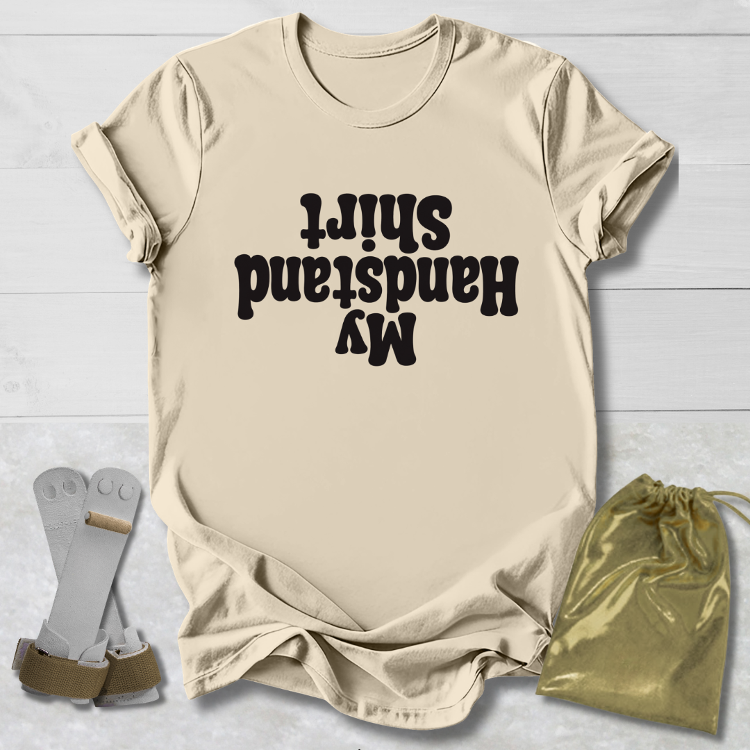Beige t-shirt with  My Handstand Shirt text, socks, and drawstring bag on a light wooden surface
