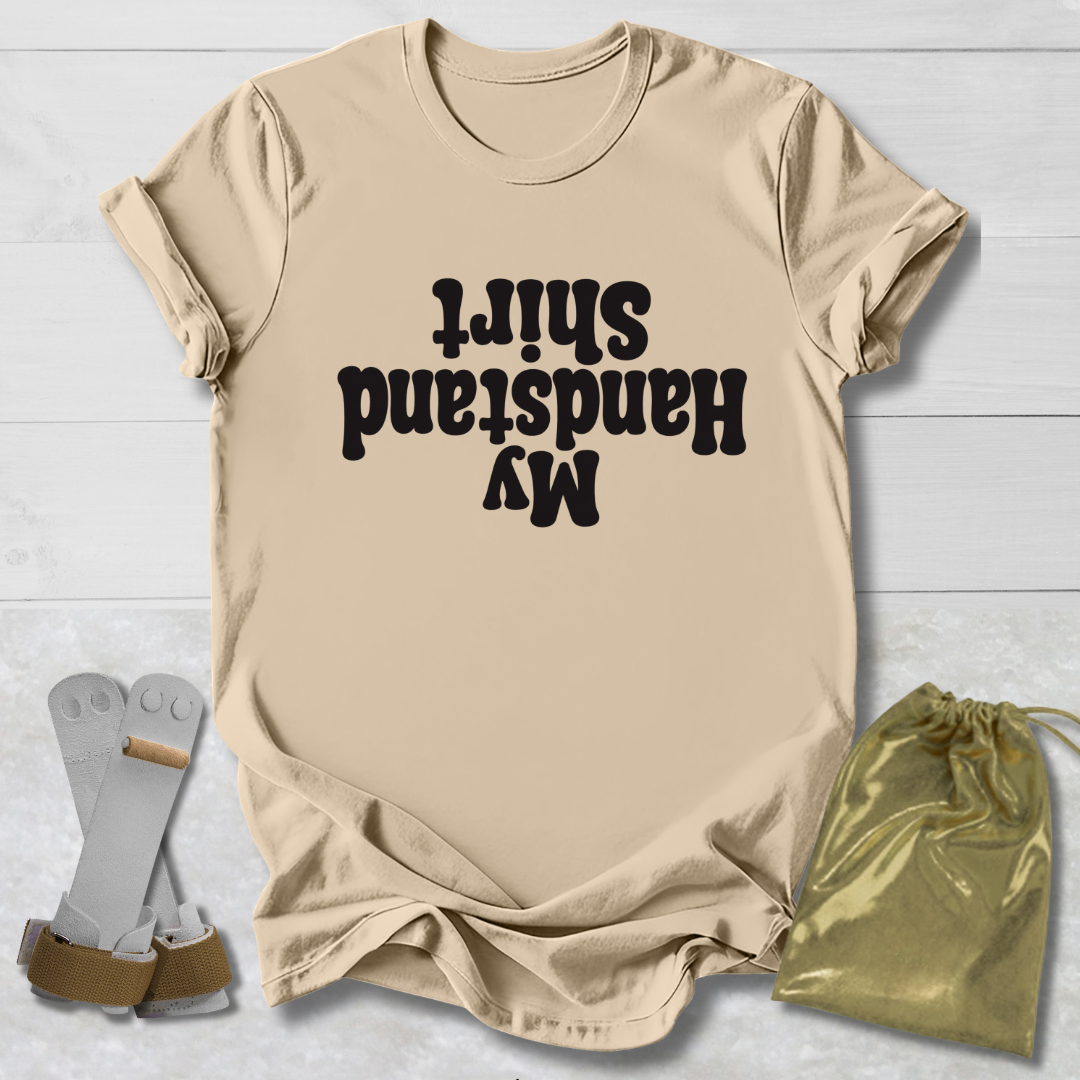 Beige t-shirt with black My Handstand Shirt text, socks, and drawstring bag on a light wooden surface