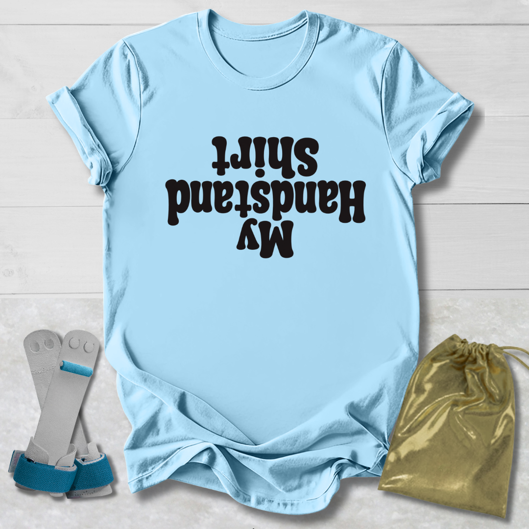 Light blue t-shirt with  My Handstand Shirt text, socks, and drawstring bag on a wooden surface
