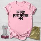 Pink t-shirt with black  My Handstand Shirt text, socks, and drawstring bag on a light wooden surface