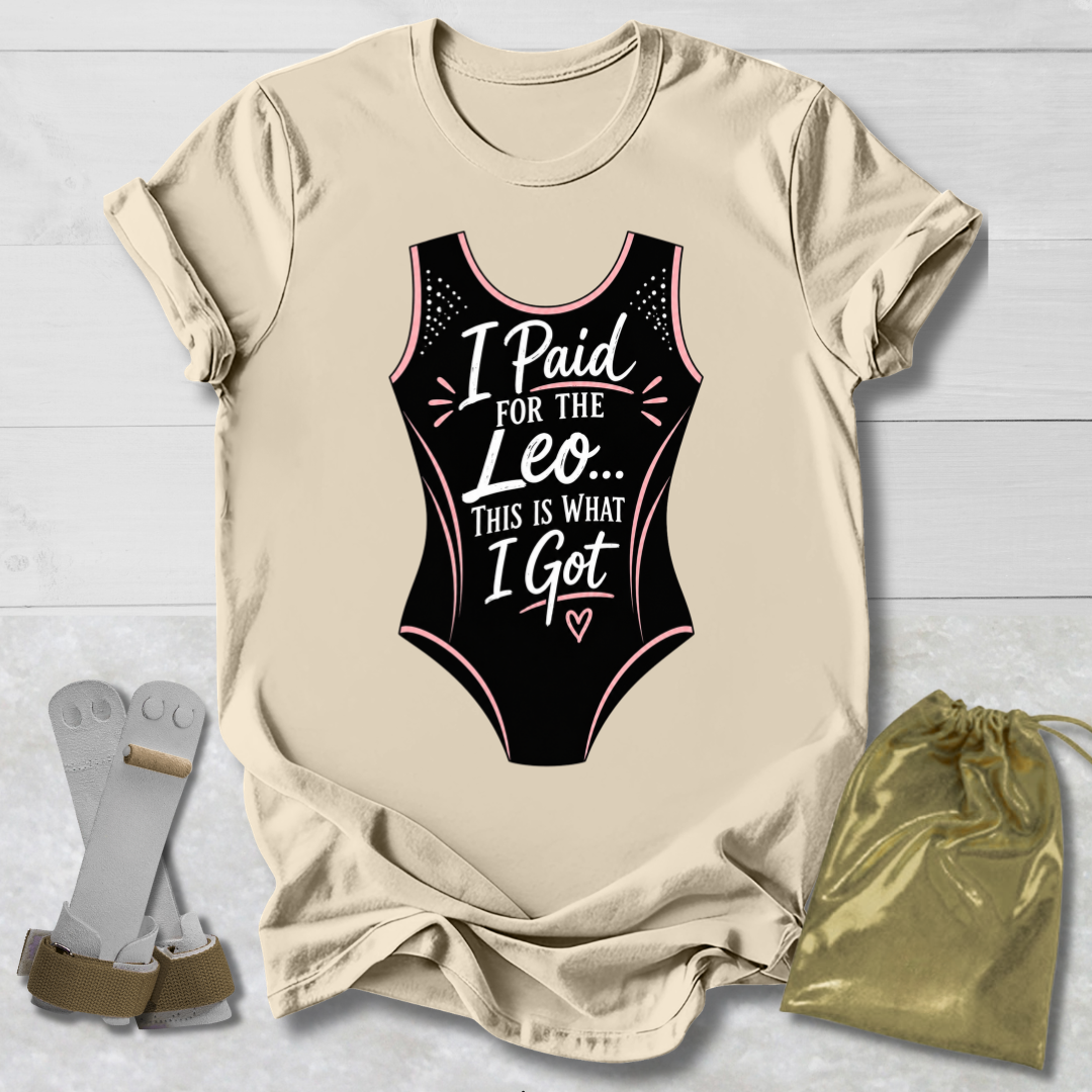 Beige t-shirt with black funny gymnastics leotard graphic and text, socks, and drawstring bag on a light wooden surface.