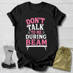 Black t-shirt with pink and white text on a wooden surface with socks and a drawstring bag.
