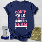Navy blue t-shirt with 'Don't talk to me during beam' text on a light wooden surface.