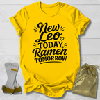 Yellow t-shirt with text 'New Leo Today, Ramen Tomorrow' on a light wooden surface.