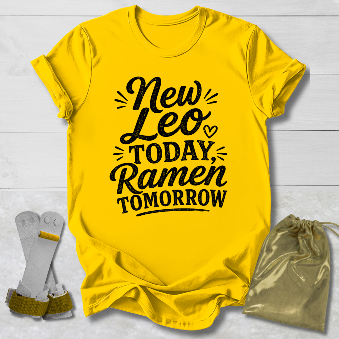 Yellow t-shirt with text 'New Leo Today, Ramen Tomorrow' on a light wooden surface.