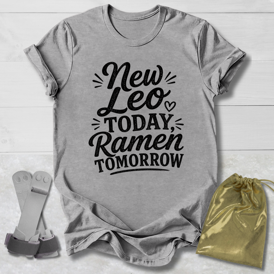 Gray t-shirt with 'New Leo Today, Ramen Tomorrow' text on a wooden surface with socks and a drawstring bag.
