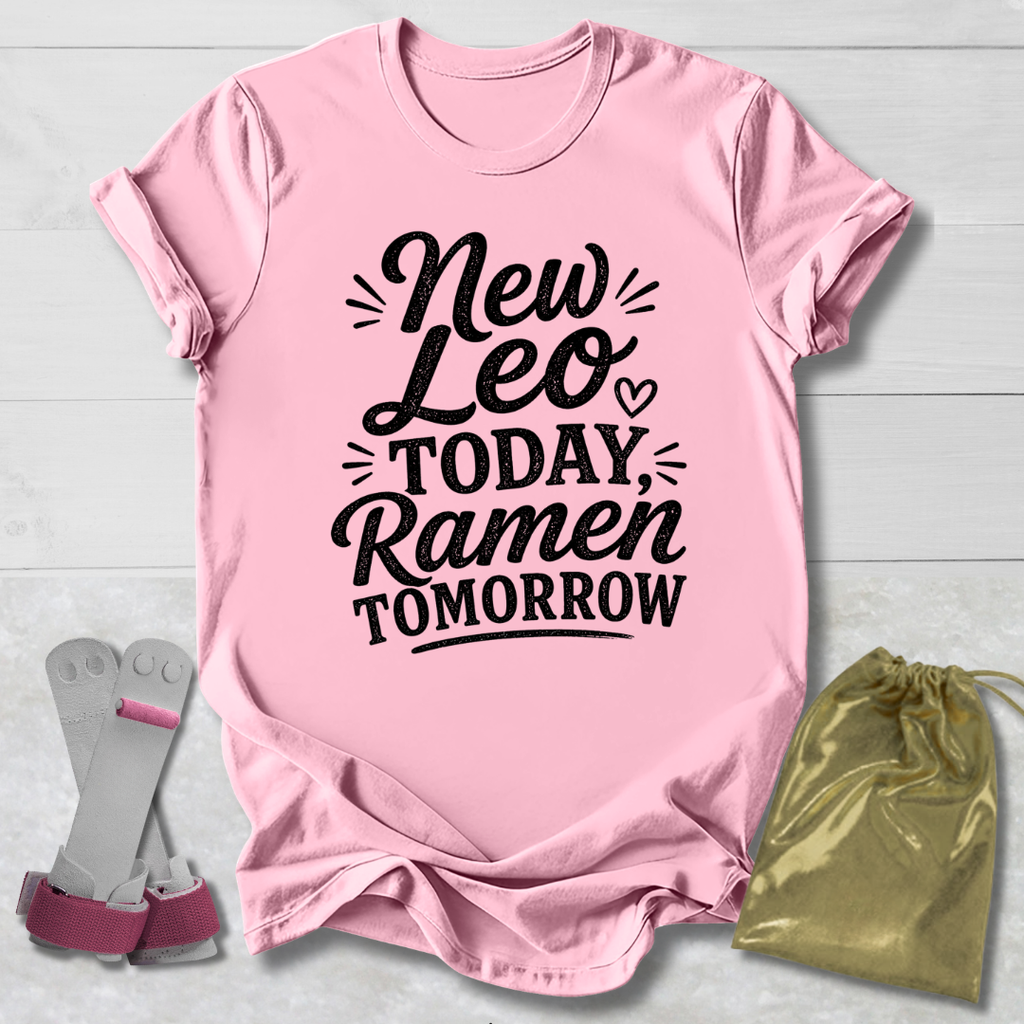 Pink t-shirt with 'New Leo Today, Ramen Tomorrow' text on a light wooden surface with socks and a drawstring bag.
