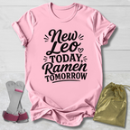 Pink t-shirt with 'New Leo Today, Ramen Tomorrow' text on a light wooden surface with socks and a drawstring bag.