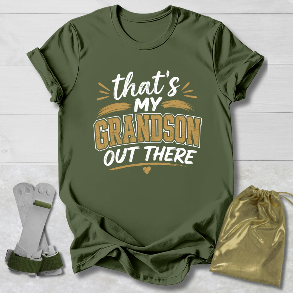 Green t-shirt with 'That's my grandson out there' text, socks, and drawstring bag on a light wooden surface.