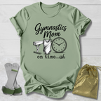 Green t-shirt with 'Gymnastics Mom on time...ish' text and graphics, socks, and drawstring bag on a light wooden surface.