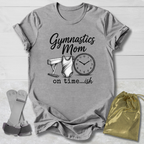 Gray t-shirt with 'Gymnastics Mom on time...ish' text and graphics, socks, and drawstring bag on a wooden surface.