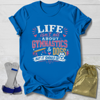 Blue t-shirt with 'Life isn't all about Gymnastics & Dogs but it should be' text on a wooden surface with socks and a drawstring bag.