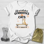 White t-shirt with gymnastics and cats design on a wooden surface with socks and a drawstring bag.