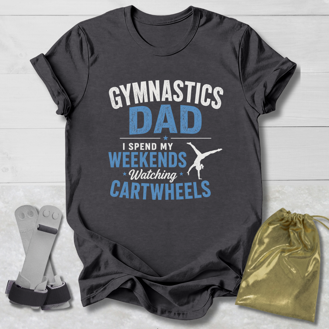 Dark gray t-shirt with 'Gymnastics Dad' text, socks, and drawstring bag on a light wooden surface