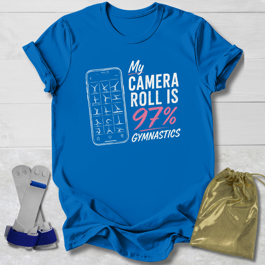 Blue t-shirt with 'My Camera Roll is 97% Gymnastics' design on a light wooden surface.