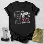 Black t-shirt with graphic and text on a light wooden surface, with socks and a drawstring bag in the foreground.
