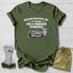 Green t-shirt with graphic and text on a wooden surface, with socks and a drawstring bag in the foreground.