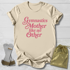 Beige t-shirt with pink text 'Gymnastics Mother like no Other' on a light wooden surface.