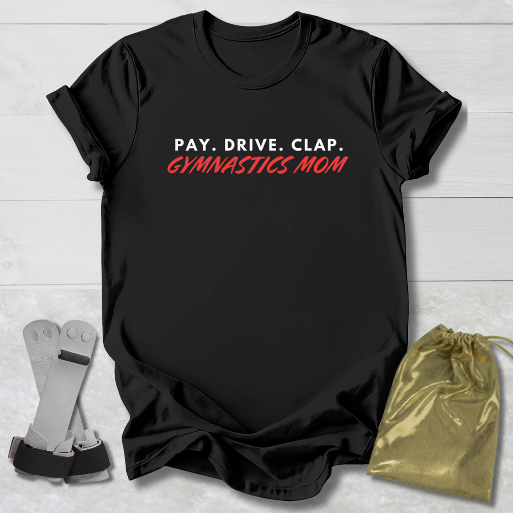 Black t-shirt with 'PAY. DRIVE. CLAP. GYMNASTICS MOM' text, socks, and drawstring bag on a light wooden surface.