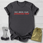 Gray t-shirt with 'PAY. DRIVE. CLAP. GYMNASTICS MOM' text, socks, and drawstring bag on a light wooden surface.
