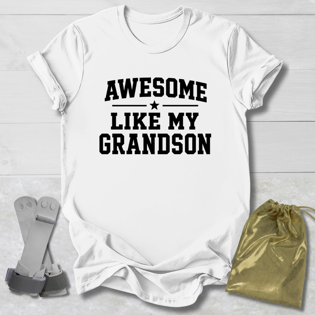 White t-shirt with 'Awesome Like My Grandson' text on a light wooden surface with socks and a drawstring bag.