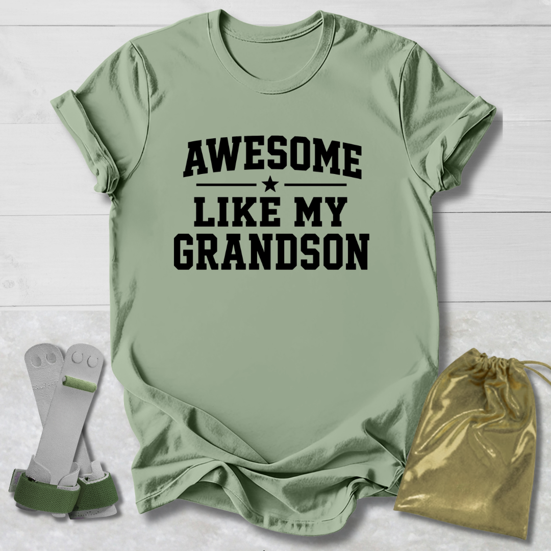 Green t-shirt with 'Awesome Like My Grandson' text, socks, and drawstring bag on a light wooden surface.