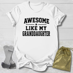 White t-shirt with 'Awesome like my granddaughter' text on a light wooden surface.