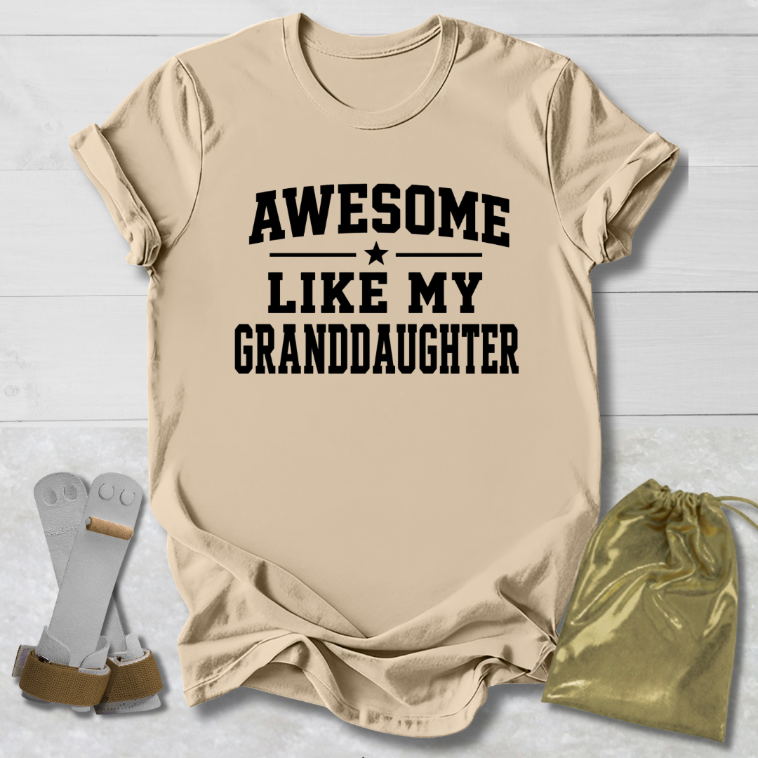 Beige t-shirt with 'Awesome like my granddaughter' text on a light wooden surface.
