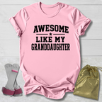 Pink t-shirt with 'Awesome Like My Granddaughter' text, socks, and drawstring bag on a light wooden surface.