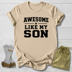Beige t-shirt with 'Awesome Like My Son' text on a light wooden surface.